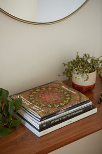 The Rebis: Wheel of Fortune magazine sits on top of a stack of magazines on a coffee table. There are plants on either side of the magazine stack.